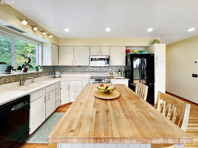 kitchen featuring black appliances, decorative backsplash, a sink, and white cabinets