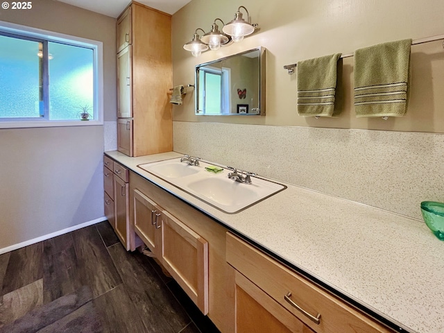 bathroom with double vanity, a sink, baseboards, and wood finished floors