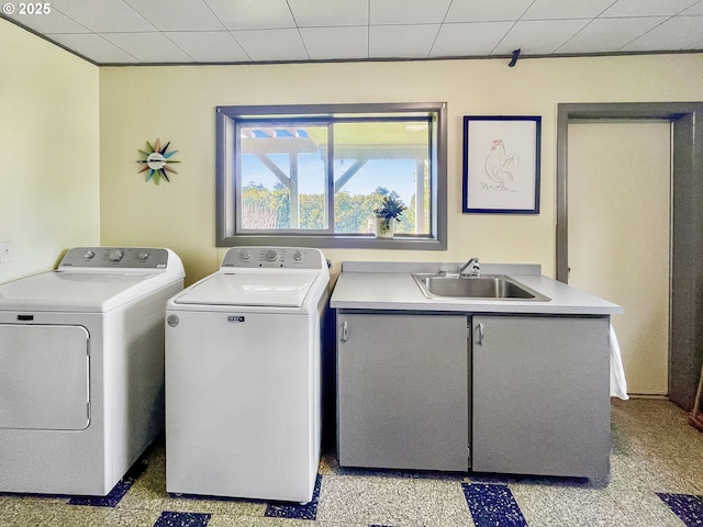clothes washing area with washing machine and dryer, a sink, and cabinet space