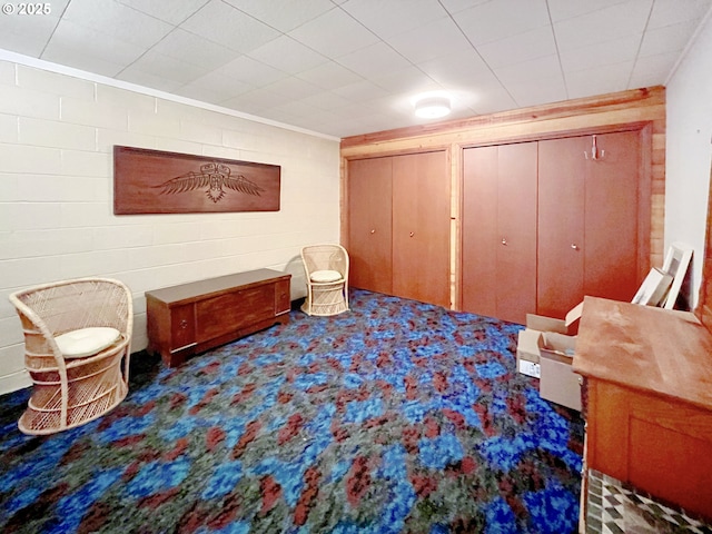 sitting room featuring concrete block wall and crown molding