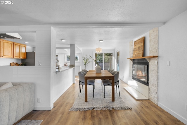 10095 SW 82nd Ave, Portland, OR 97223 - dining space featuring wood finished floors, a fireplace, baseboards, and a textured ceiling