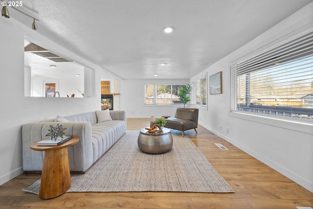 10095 SW 82nd Ave, Portland, OR 97223 - living room with baseboards, a glass covered fireplace, wood finished floors, a textured ceiling, and recessed lighting