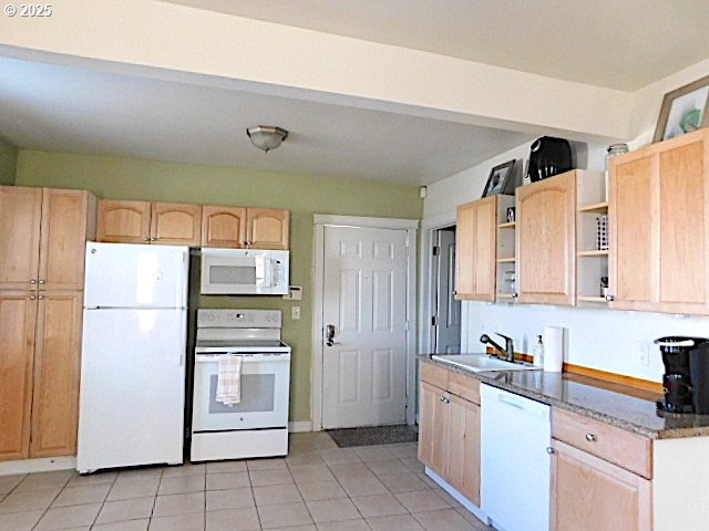 kitchen featuring light brown cabinets, white appliances, light tile patterned floors, and sink