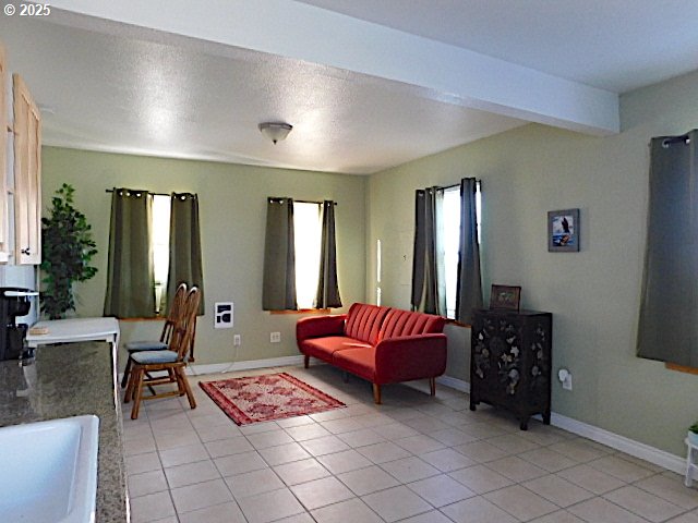 living room featuring light tile patterned floors, beam ceiling, and sink