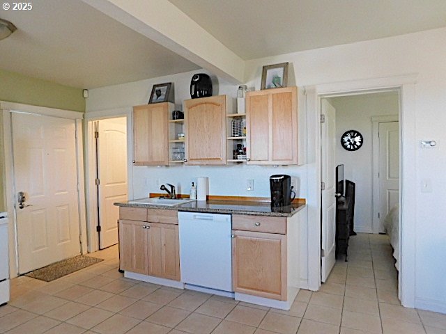 kitchen with light brown cabinetry, dishwasher, light tile patterned floors, and sink