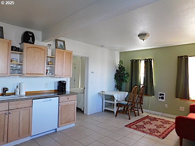 kitchen featuring dishwasher, light brown cabinets, sink, light tile patterned floors, and a textured ceiling