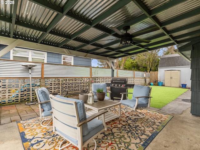 view of patio with area for grilling, fence, a storage shed, an outdoor structure, and ceiling fan