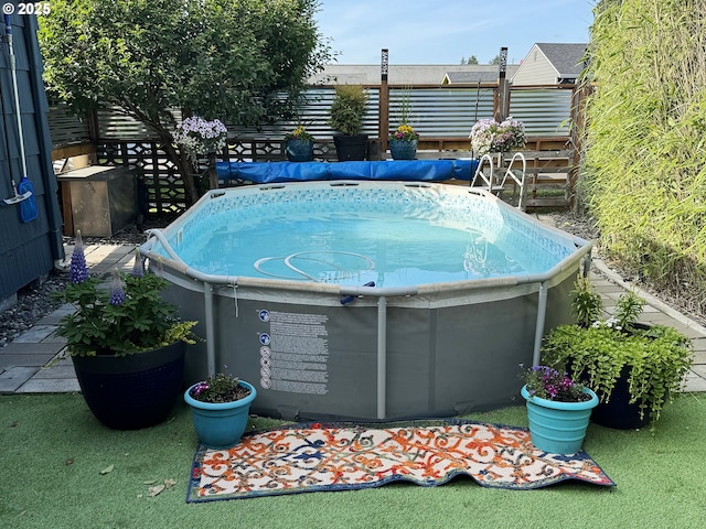 view of pool with a jacuzzi and fence