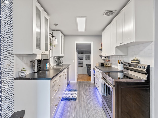 kitchen featuring visible vents, a sink, stainless steel appliances, white cabinets, and dark countertops