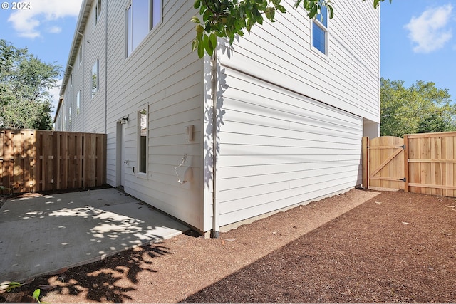 view of side of property with a patio, a gate, and fence