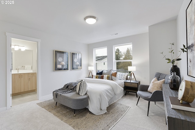 bedroom with ensuite bath, light colored carpet, visible vents, and baseboards