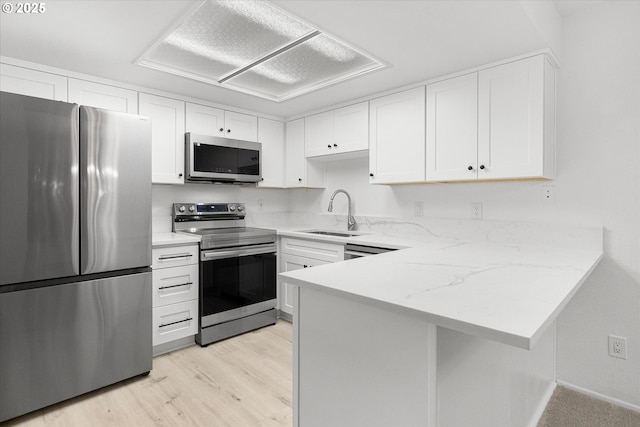 86 Kingsgate Rd Unit D204, Lake Oswego, OR 97035 - kitchen with stainless steel appliances, a sink, white cabinets, a peninsula, and light wood-style flooring