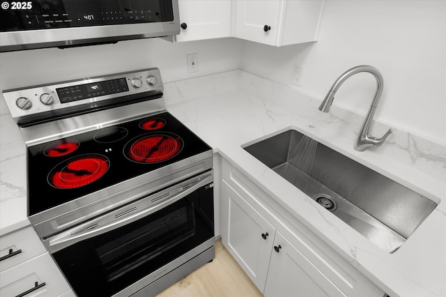 86 Kingsgate Rd Unit D204, Lake Oswego, OR 97035 - kitchen with stainless steel appliances, a sink, white cabinetry, and light stone countertops