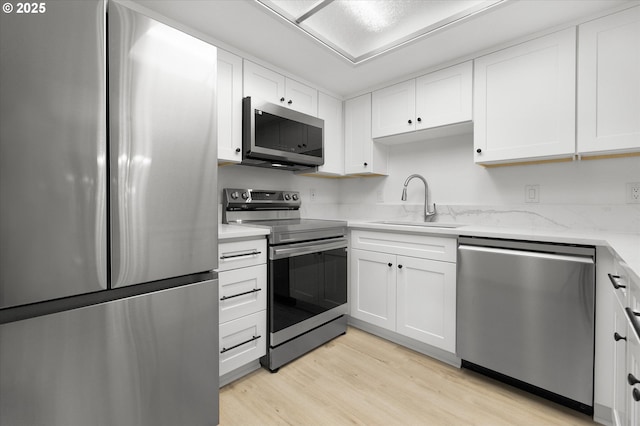 86 Kingsgate Rd Unit D204, Lake Oswego, OR 97035 - kitchen with appliances with stainless steel finishes, a sink, light wood-style floors, white cabinets, and light stone countertops