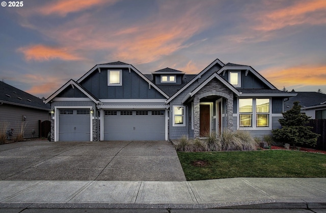 craftsman inspired home with board and batten siding, a front yard, driveway, stone siding, and an attached garage