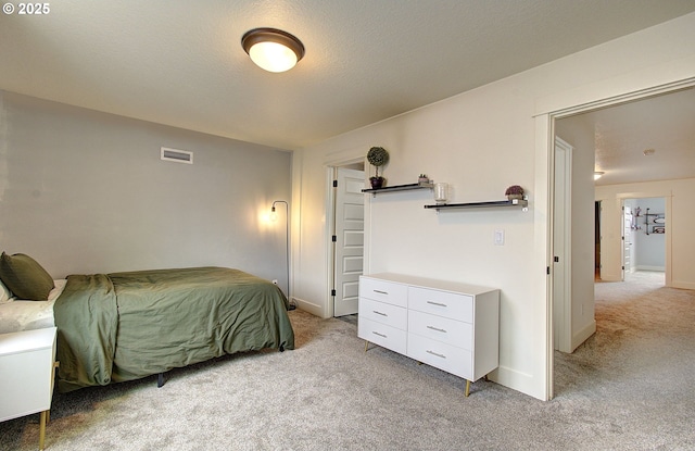 bedroom with visible vents, baseboards, light colored carpet, and a textured ceiling