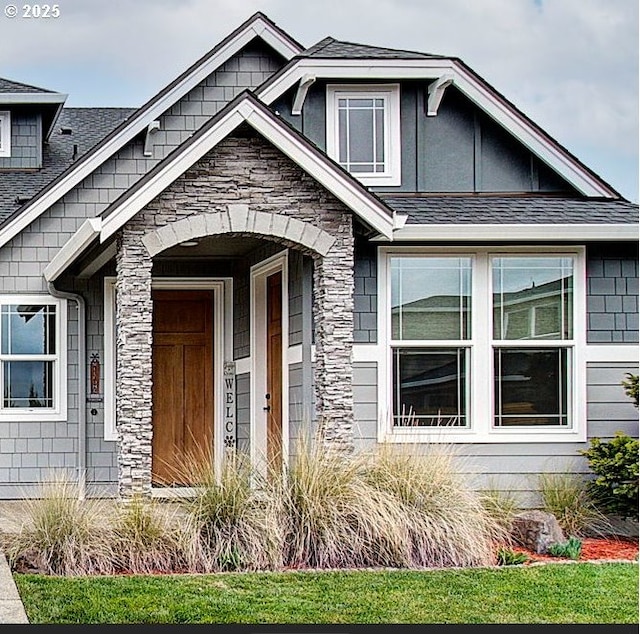 view of front of house with stone siding and roof with shingles