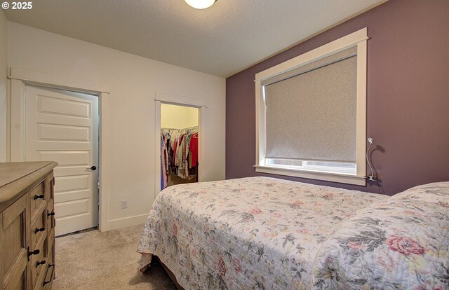 bedroom with baseboards, light colored carpet, and a textured ceiling