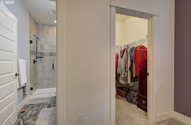 full bath featuring a walk in closet, baseboards, and a shower stall