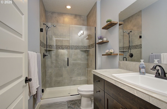 bathroom with toilet, a stall shower, vanity, and a textured ceiling