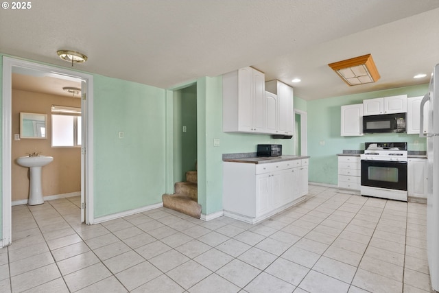 kitchen with light tile patterned floors, sink, white cabinets, and white stove