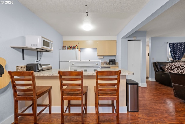 kitchen with white appliances, dark wood-type flooring, cream cabinets, light countertops, and a textured ceiling