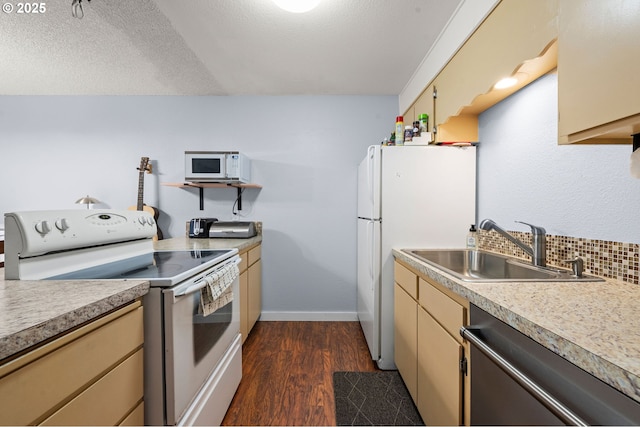 kitchen with dark wood finished floors, light countertops, decorative backsplash, a sink, and white appliances