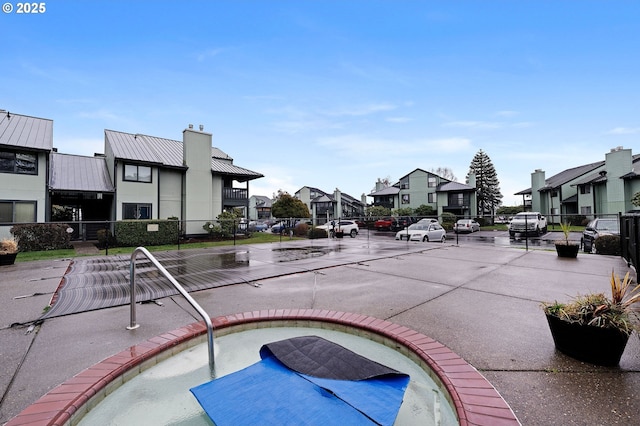 exterior space featuring a residential view, a jacuzzi, and fence