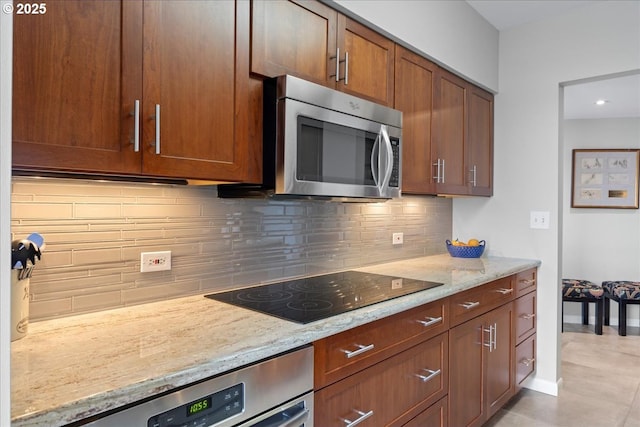 kitchen featuring black electric stovetop, light stone counters, wall oven, decorative backsplash, and stainless steel microwave