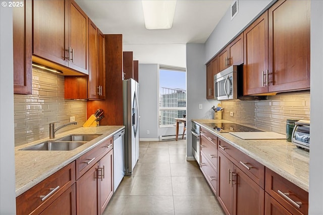 kitchen with light tile patterned floors, appliances with stainless steel finishes, a sink, and light stone counters