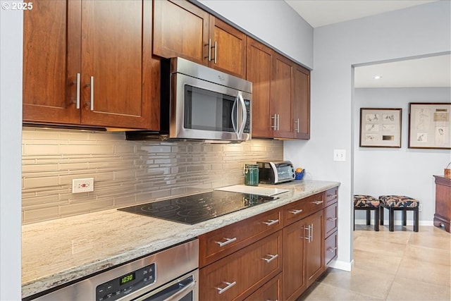 kitchen featuring wall oven, decorative backsplash, stainless steel microwave, light stone counters, and black electric stovetop