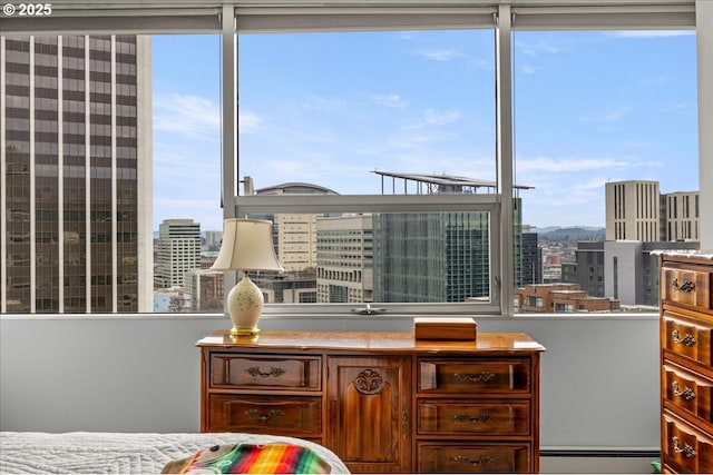 bedroom with a baseboard heating unit, a city view, and multiple windows