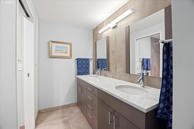 bathroom featuring double vanity, baseboards, a sink, and tile patterned floors