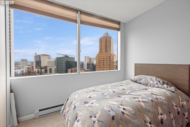 bedroom with a baseboard heating unit, a view of city, carpet floors, and baseboards