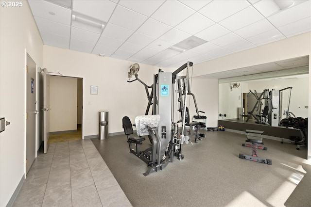 exercise area with a paneled ceiling and baseboards