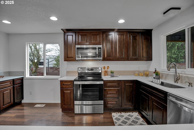 kitchen with a sink, light countertops, dark wood finished floors, and stainless steel appliances