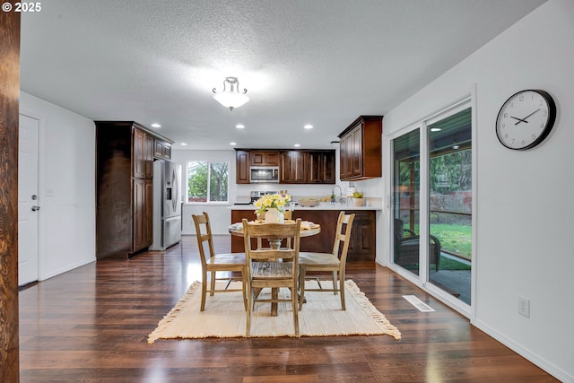 dining space featuring dark wood finished floors, recessed lighting, baseboards, and a textured ceiling