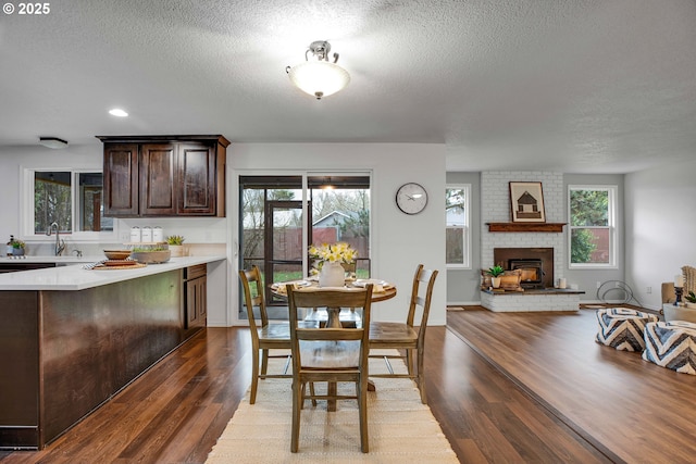 dining area featuring a fireplace, wood finished floors, a wealth of natural light, and a textured ceiling