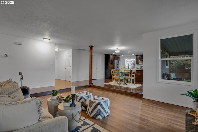 living room with a textured ceiling, baseboards, and wood finished floors