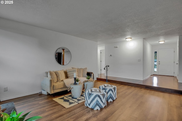 living room featuring a textured ceiling, baseboards, and wood finished floors