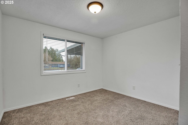 carpeted empty room with visible vents, a textured ceiling, and baseboards