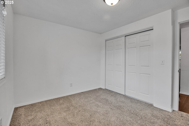 unfurnished bedroom featuring a closet, carpet floors, a textured ceiling, and baseboards