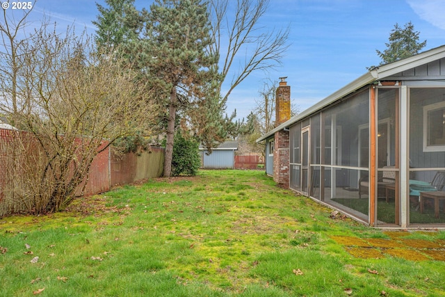 view of yard with an outdoor structure, a fenced backyard, and a sunroom