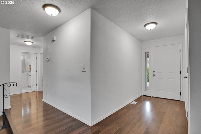 entrance foyer featuring visible vents, baseboards, a textured ceiling, and dark wood-style flooring