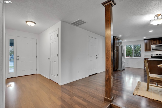 entryway with visible vents, dark wood-style flooring, and ornate columns