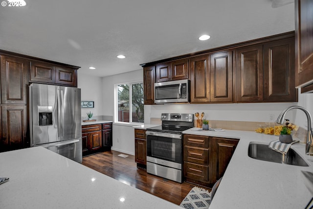 kitchen with dark wood-style flooring, dark brown cabinets, stainless steel appliances, and a sink