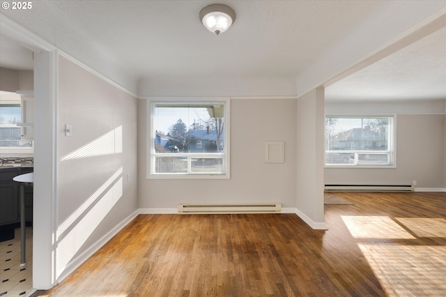 empty room with wood-type flooring and a baseboard heating unit