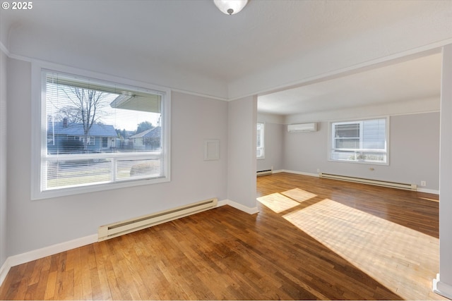 spare room with wood-type flooring, an AC wall unit, and baseboard heating