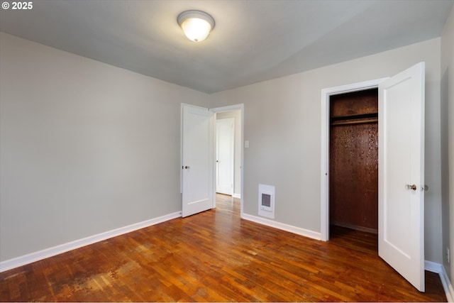 unfurnished bedroom featuring a closet and dark hardwood / wood-style floors