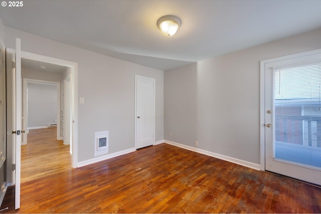 empty room with heating unit, a baseboard radiator, and dark hardwood / wood-style floors